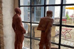Bild zeigt Blick aus Fenster der Skulpturenwerkstatt Herr Harms. Auf dem Fensterbrett stehen zwei Skulpturen aus Ton und blicken aus dem Fenster.